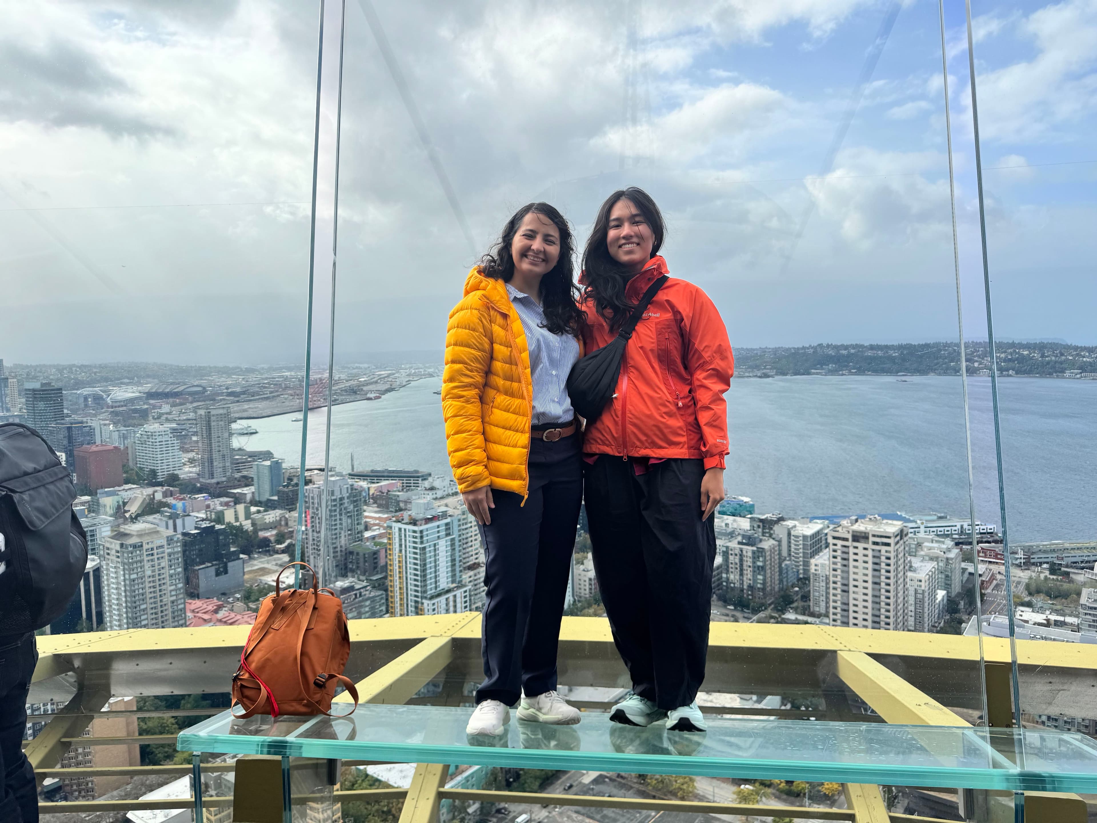 Two Meadow teammates smiling together on the Space Needle's glass observation deck