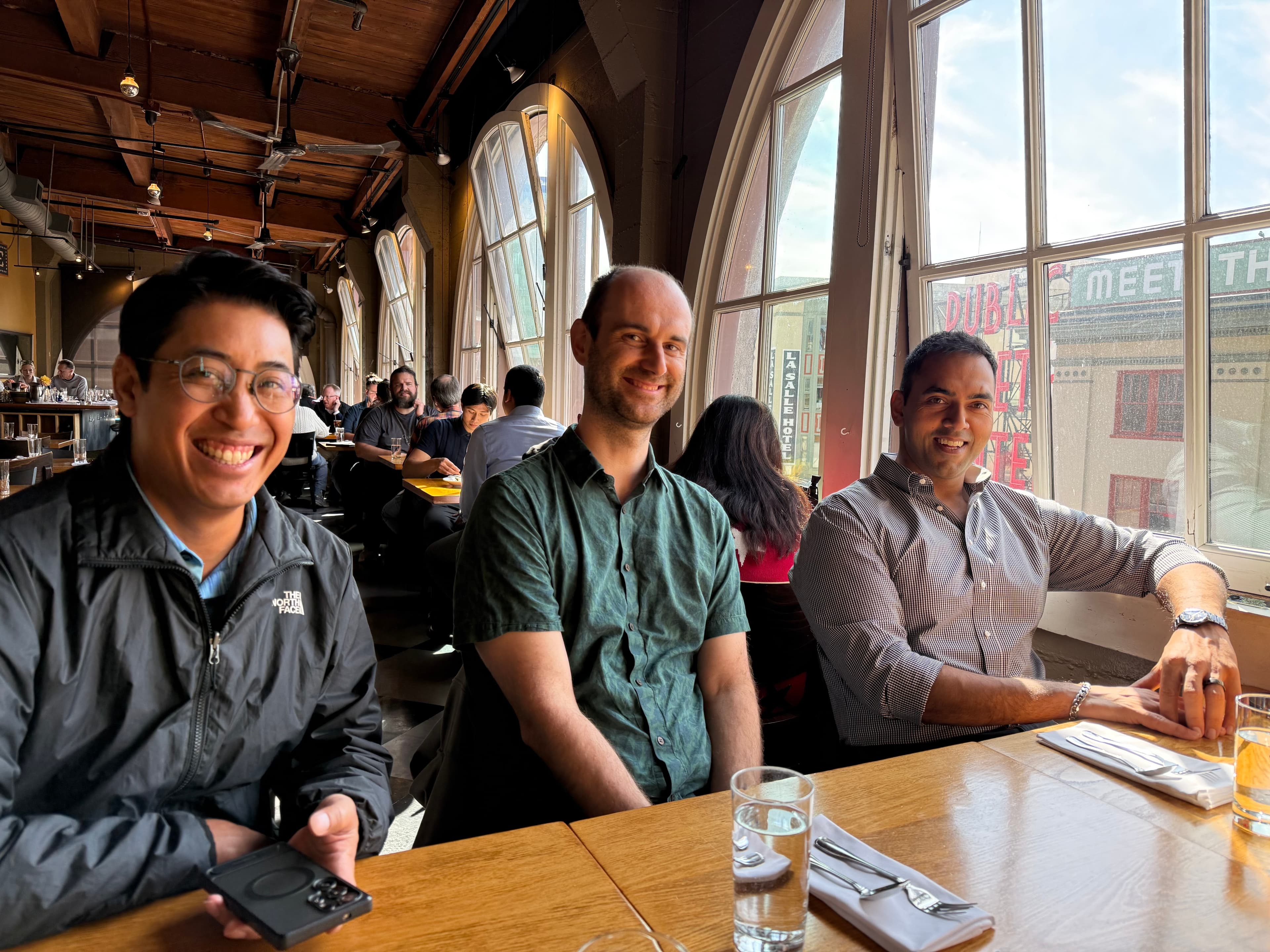 Three Meadow teammates smiling together at a restaurant table