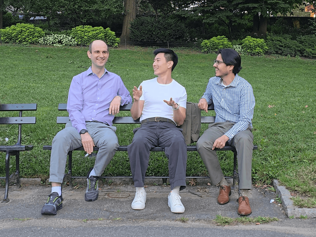 Three Meadow co-founders sitting together on a park bench, in conversation