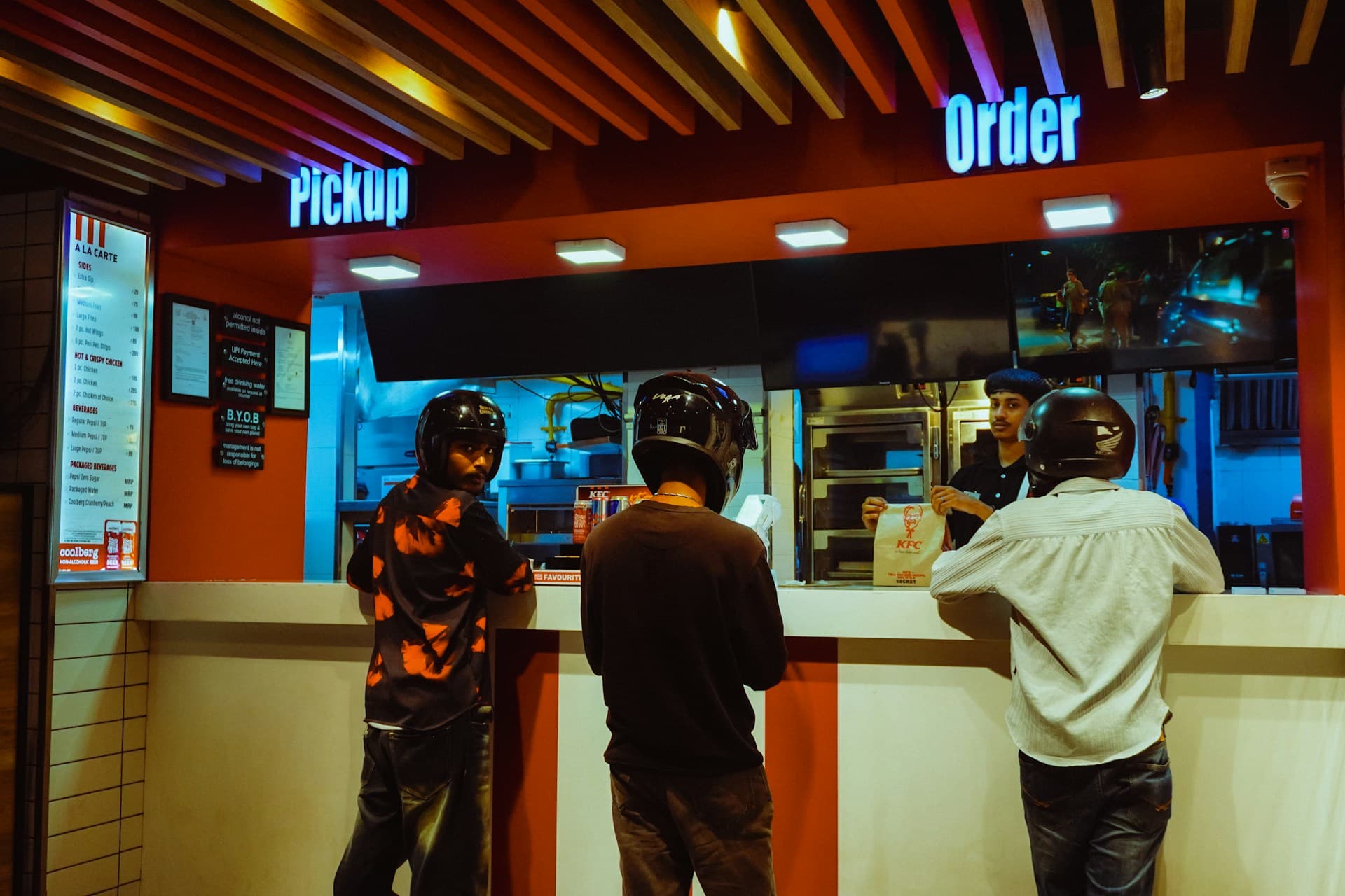 Customers ordering at a lit quick-service counter at night